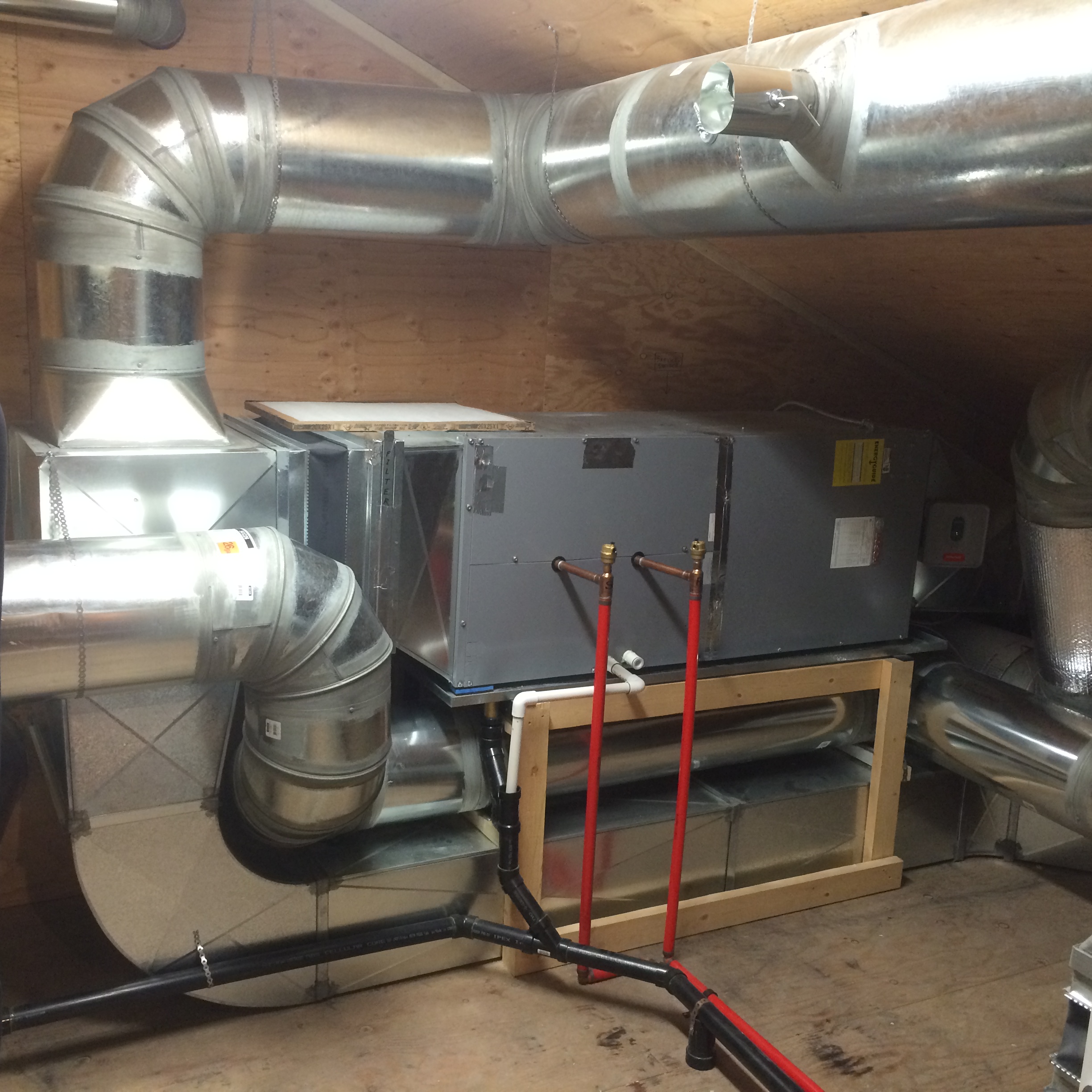 Horizontal air handler unit installed in mechanical room with ductwork